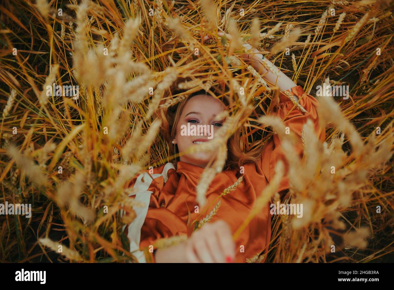 The girl in wheat lies in a dress and laughs. Golden spikelets of ...