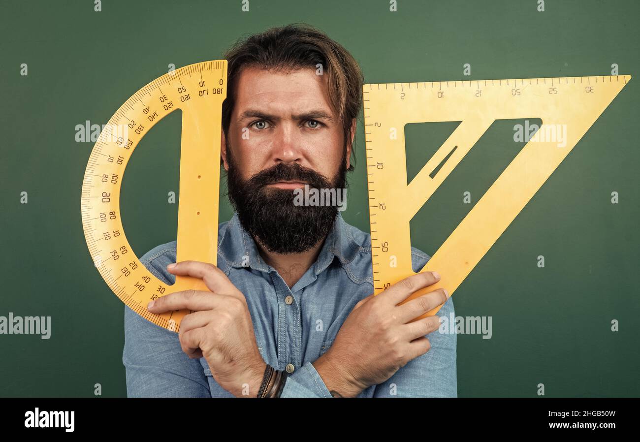 formal education. measure and size. serious teacher hold triangle and protractor tool. bearded man work in classroom with ruler. prepare for geometry Stock Photo