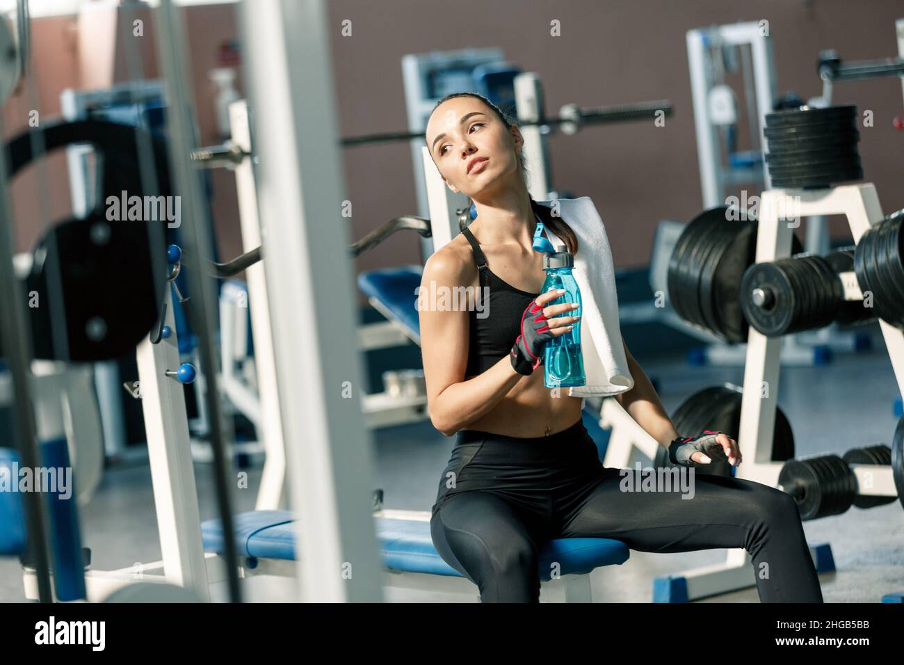 Lifestyle portrait of a young sporty woman with a white towel over her ...