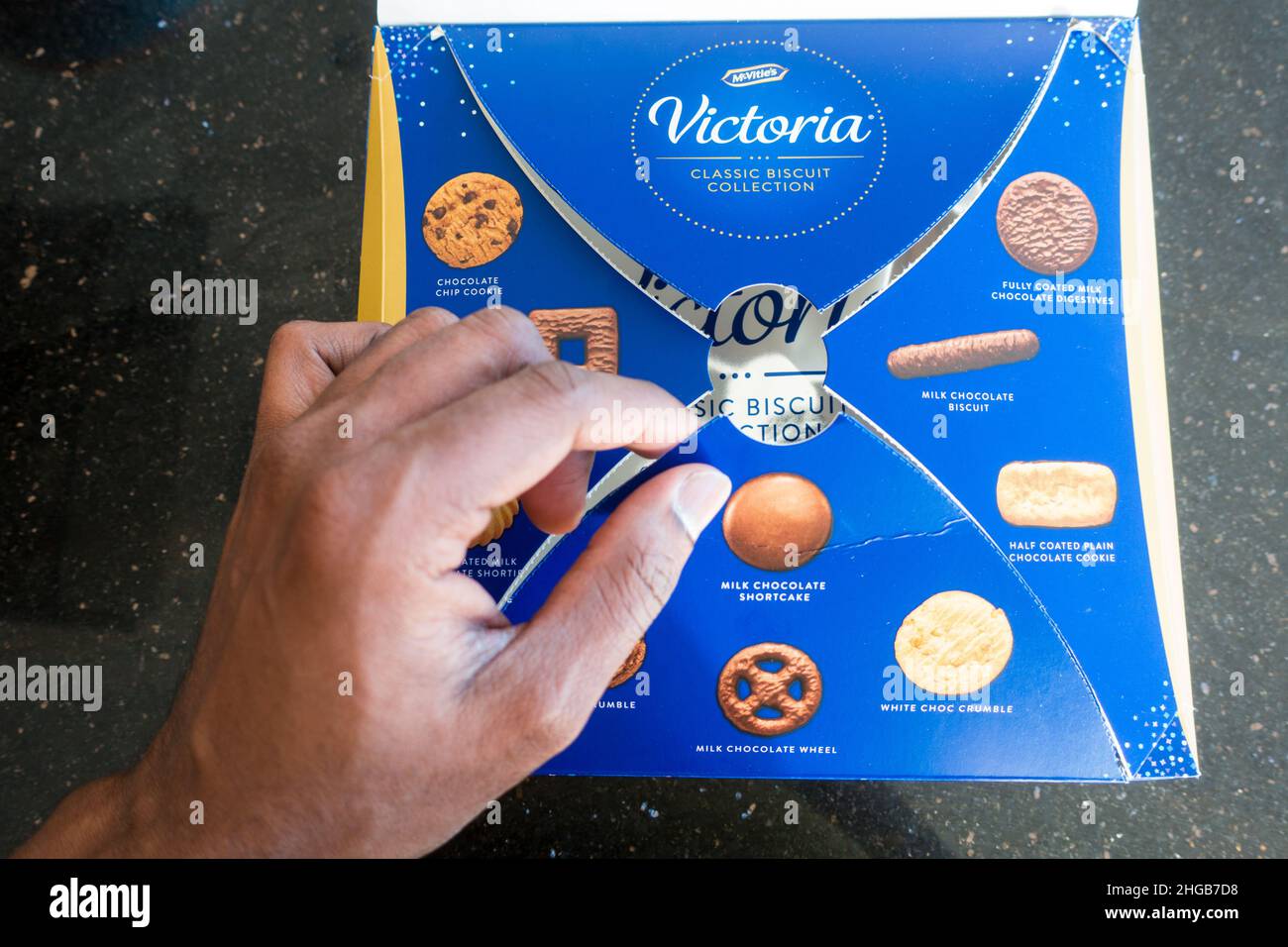 Adult Asian male opening McVities Victoria biscuit selection Stock Photo