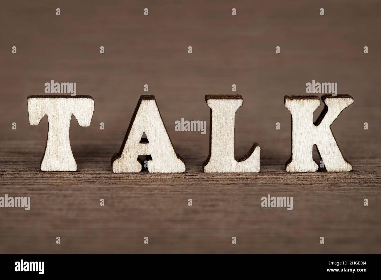 Word 'talk' made with wooden letters on wooden board background. Stock Photo