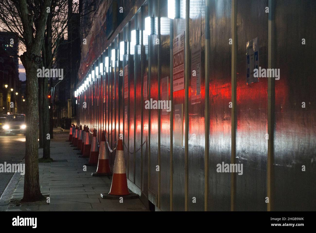 London, UK, 16 Jan 2022: As night falls on George Street in Marylebone the hoardings of a construction site reflect traffic lights. Anna Watson/Alamy Stock Photo