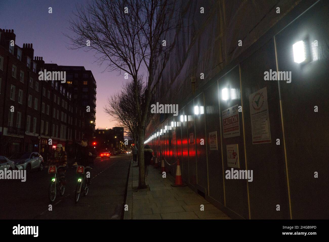 London, UK, 16 Jan 2022: As night falls on George Street in Marylebone the hoardings of a construction site reflect traffic lights. Anna Watson/Alamy Stock Photo