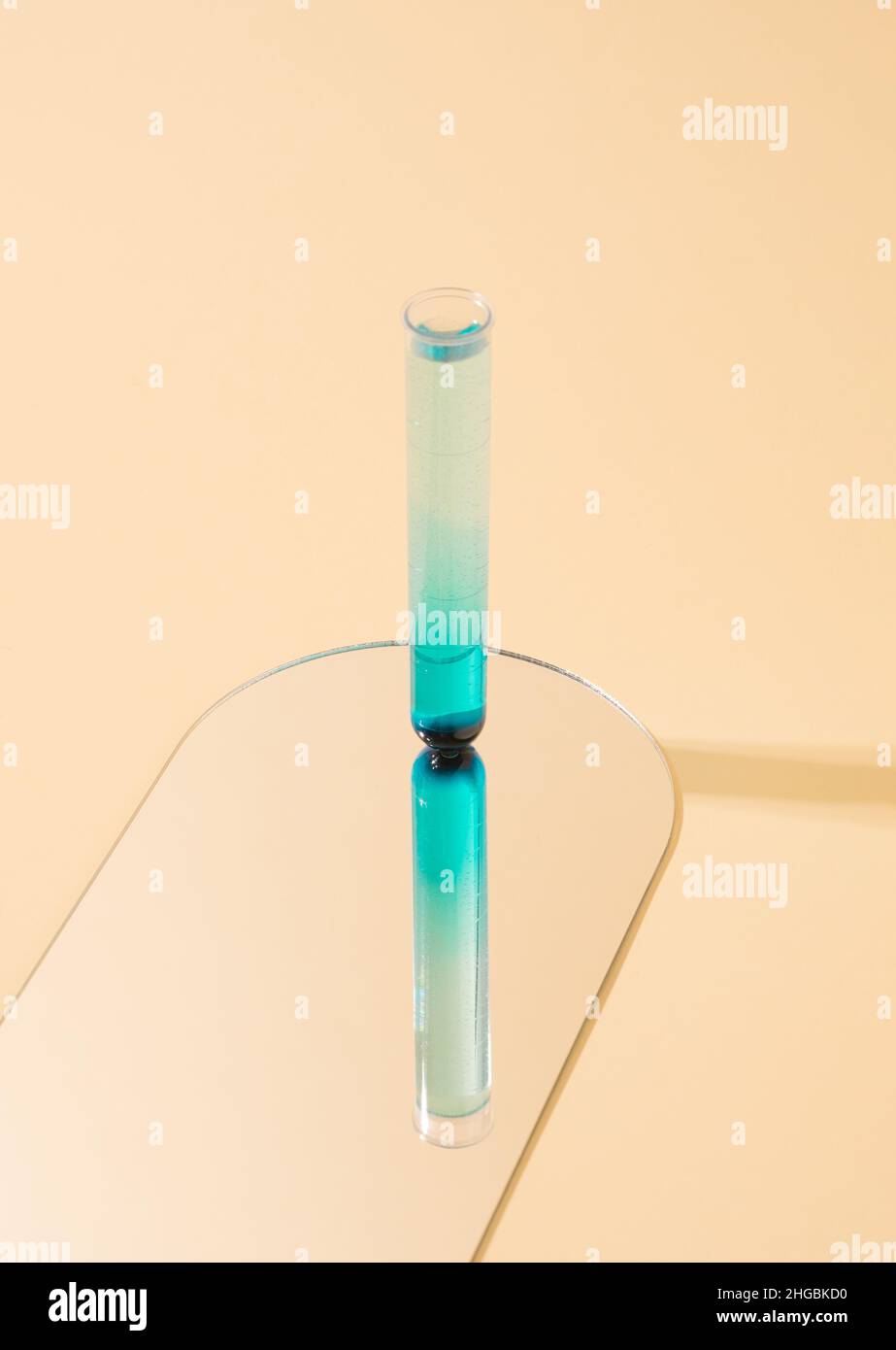 Single test tube standing on a mirror on a yellow background