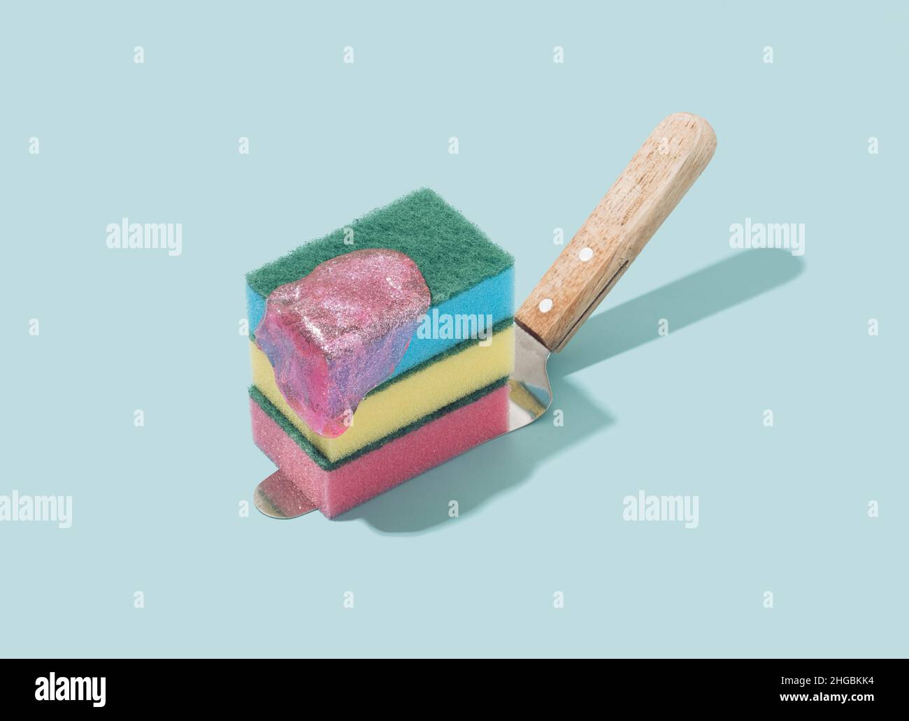 Cake spatula with colorful sponges and pink slime on a pastel blue background. Future past retro concept. Stock Photo