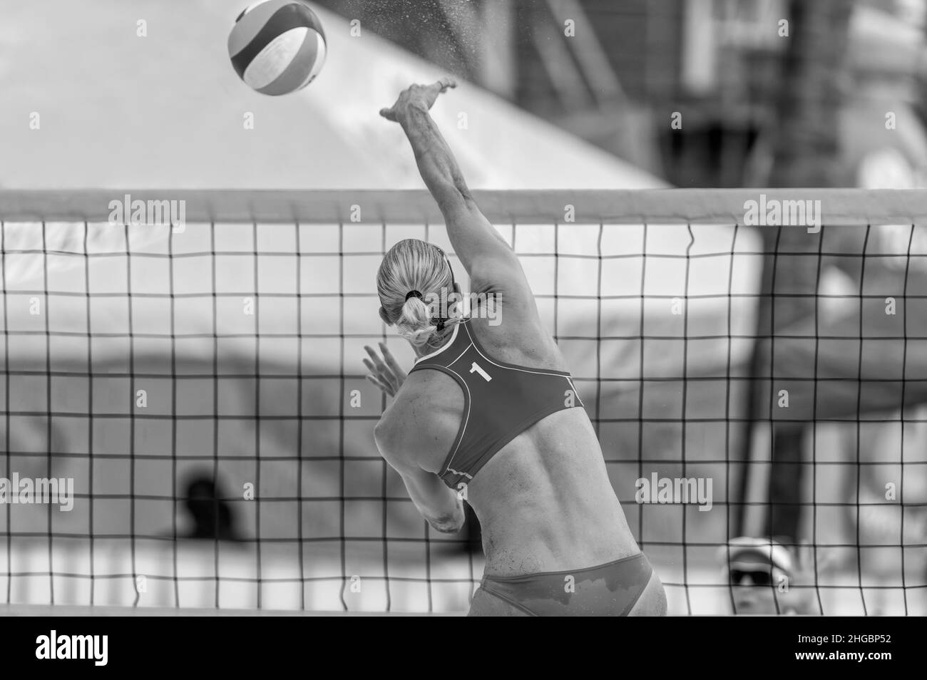 A Female Beach Volleyball Player Is Jumping At the Net And Spiking The