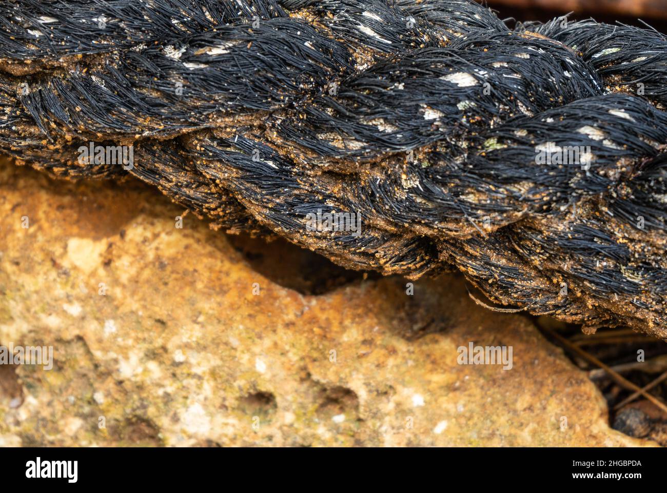 old, worn-out black braided rope for mooring ships on the rocks Stock ...