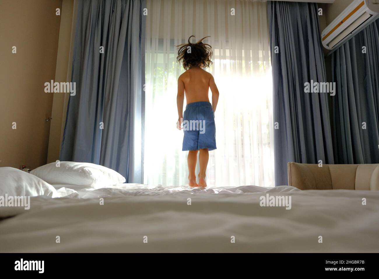 Two happy kids jumping on the bed with a phone listening to music Stock Photo