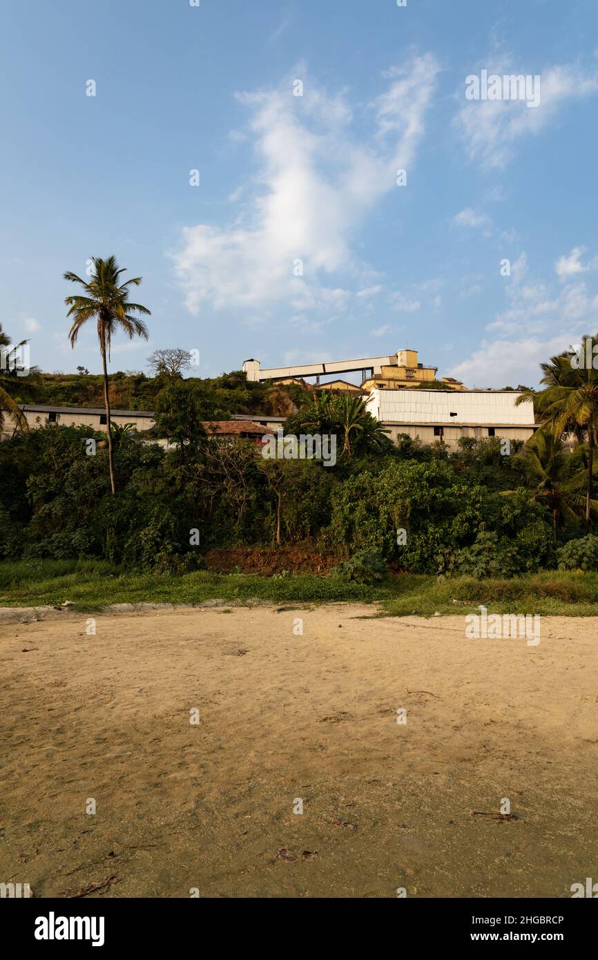 Massive Zuari Agro Chemicals Limited industry, hiding behind coconut palm trees, overlooking Velsao beach near Sankval, Mormugao, Goa, India Stock Photo