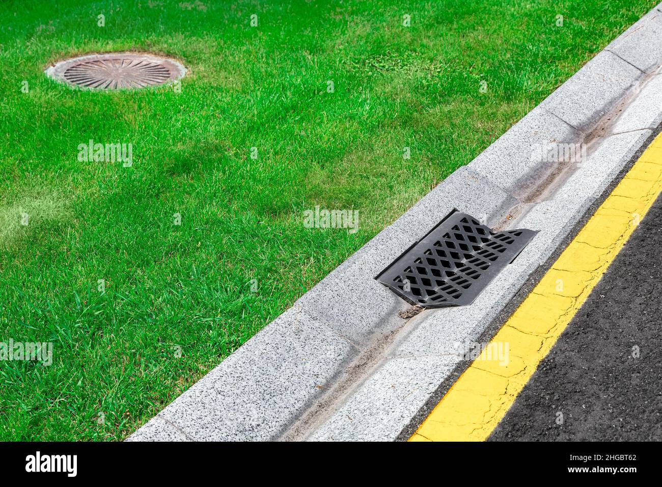 gray gutter of a stormwater drainage system on the side of asphalt road