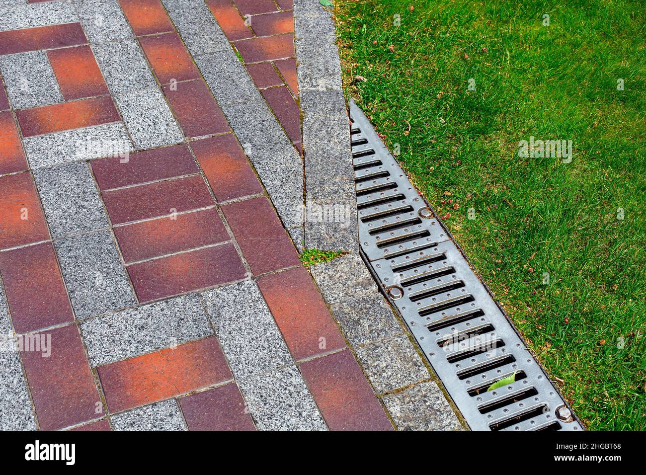 drainage grate bolted to storm drain at corner of pedestrian pavement