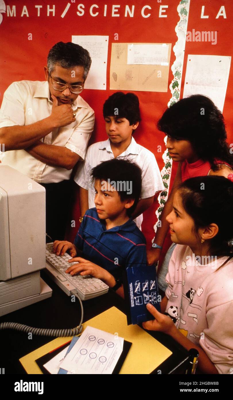 Austin, Texas USA 1990: Hispanic 5th graders at computer lab with teacher supervising. MR ES-035. Stock Photo