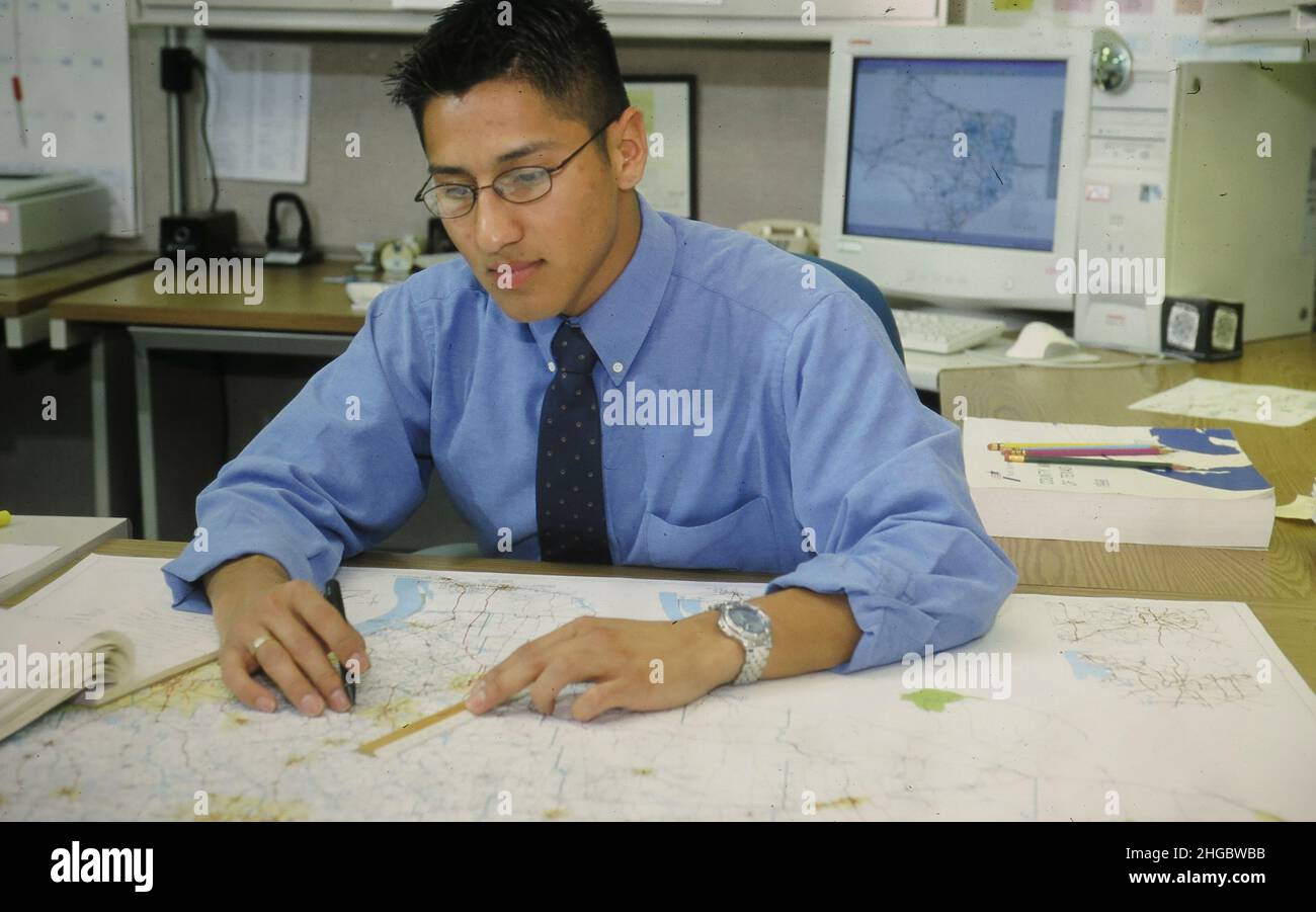 Austin, Texas USA 2002 Hispanic Texas Dept. of Transportation worker working with state maps. MR SH-039 ©Bob Daemmrich Stock Photo