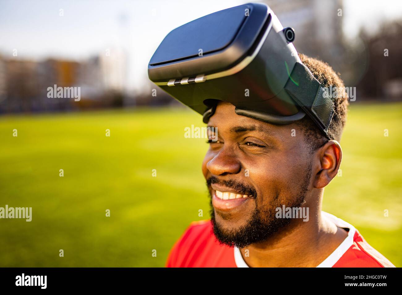 happy man in virtual reality glasses in football field background is blurred concept of virtual reality outdoors summer sunny day Stock Photo