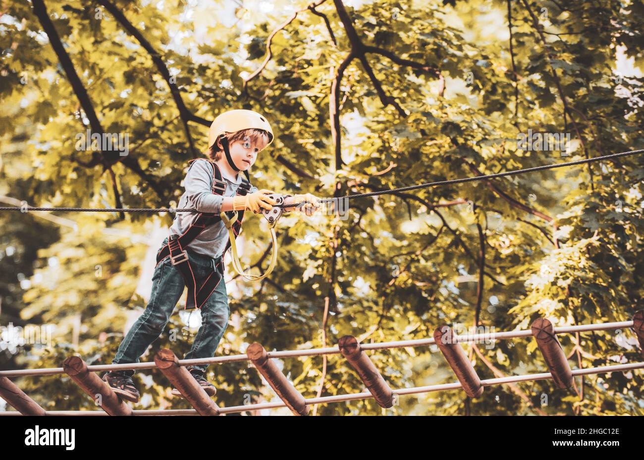 Balance beam and rope bridges. Go Ape Adventure. Child concept. Climber child on training. Portrait of a beautiful kid on a rope park among trees Stock Photo