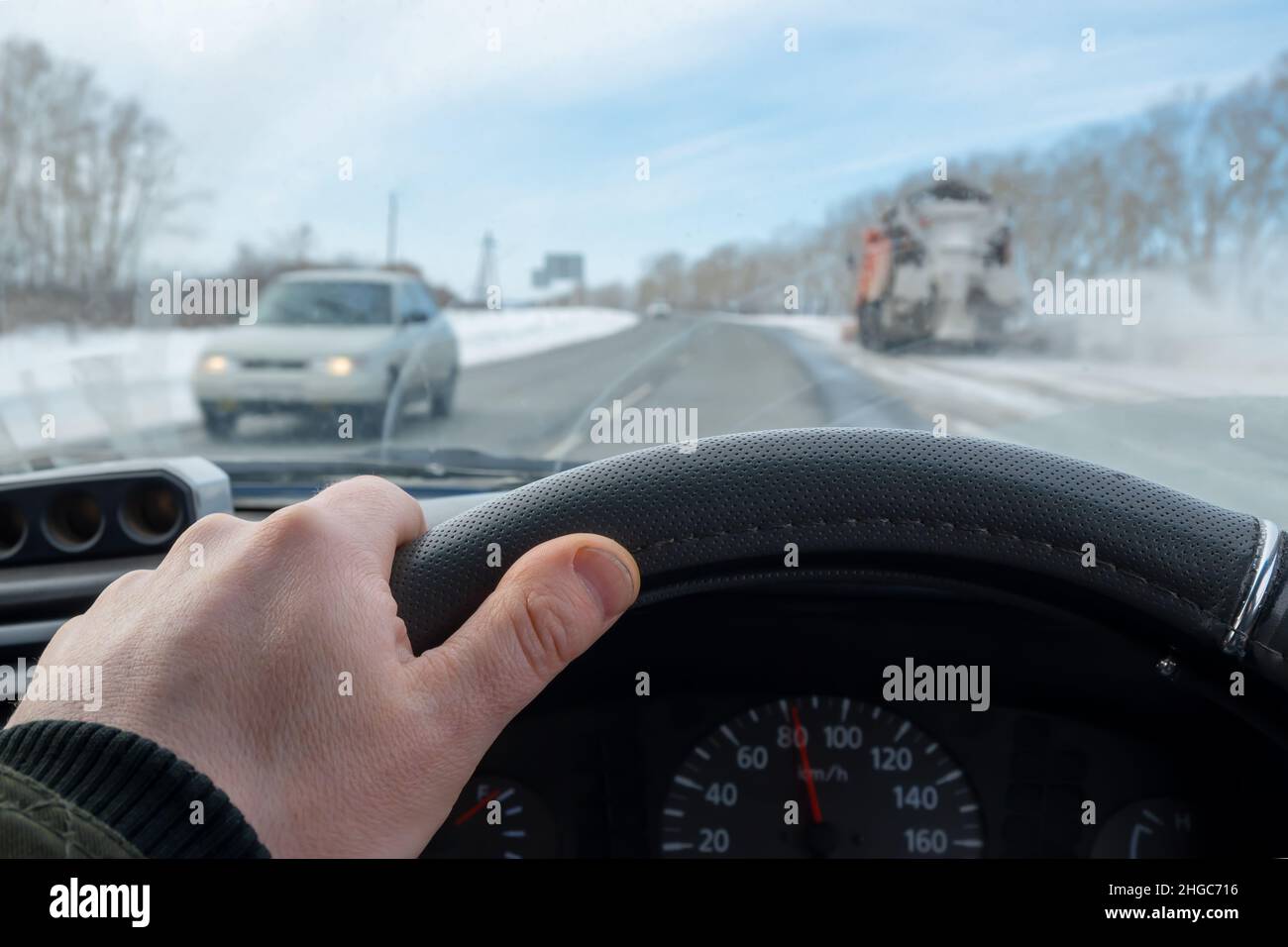 driver hand is on the steering wheel inside the car, which is driving