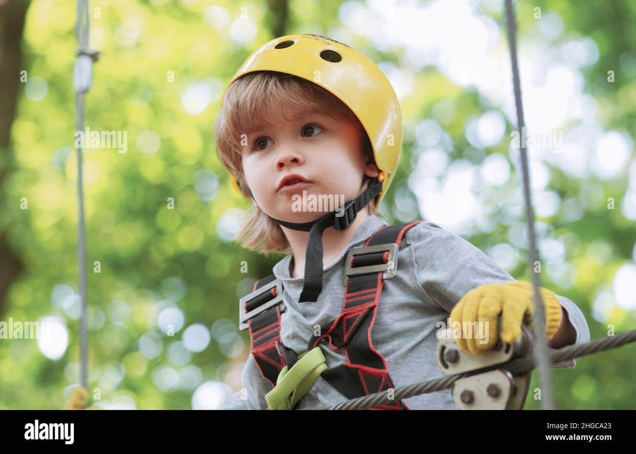 High ropes walk. Helmet and safety equipment. Child concept. Happy Little child climbing a tree