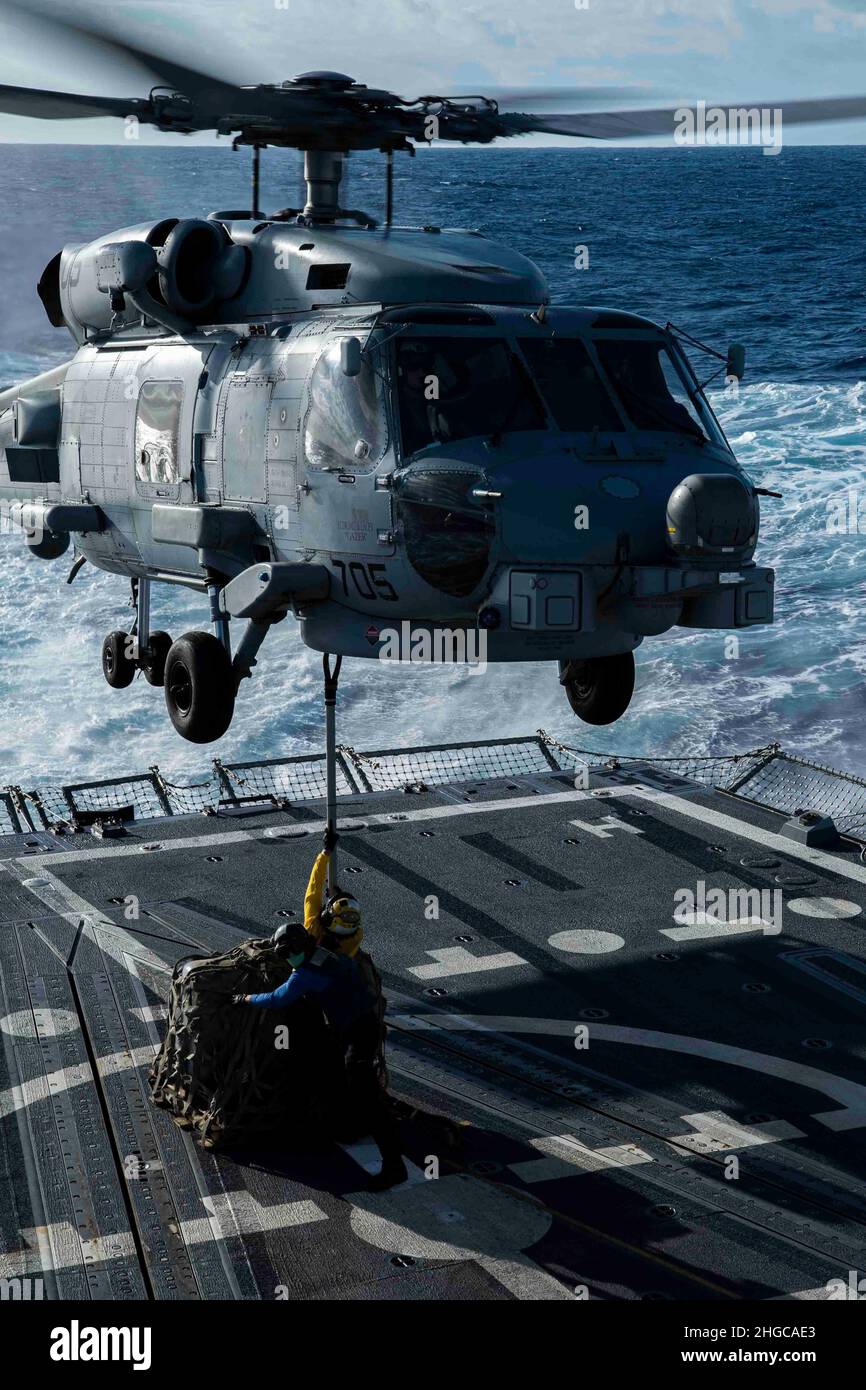 PACIFIC OCEAN (Jan. 17, 2022) Boatswain’s Mate Seaman Lissa Herrera, from Hackensack, N.J., and Boatswain’s Mate Seaman Bobby J. Cunningham, from Arlington, Texas, attach a cargo hook to an MH-60R Sea Hawk helicopter, assigned to the “Raptors” of Helicopter Maritime Strike Squadron (HSM) 71, during a vertical replenishment exercise aboard the Arleigh Burke-class guided-missile destroyer USS Gridley (DDG 101). Abraham Lincoln Strike Group is on a scheduled deployment in the U.S. 7th Fleet area of operations to enhance interoperability through alliances and partnerships while serving as a ready- Stock Photo