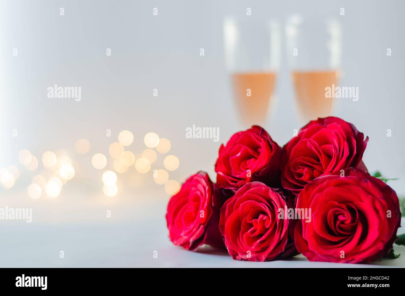 Red roses with glasses of sparkling Rose wine on white background with ...