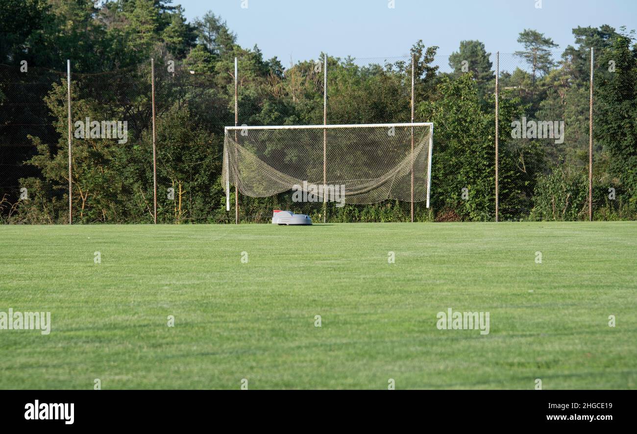 the lawn of a football field is trimmed by a robotic lawn mower Stock