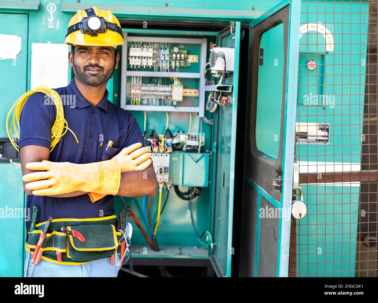 happy smiling Electrician with crossed arms and safety precautions standing by looking at camera - concept of skilled professional occupation Stock Photo