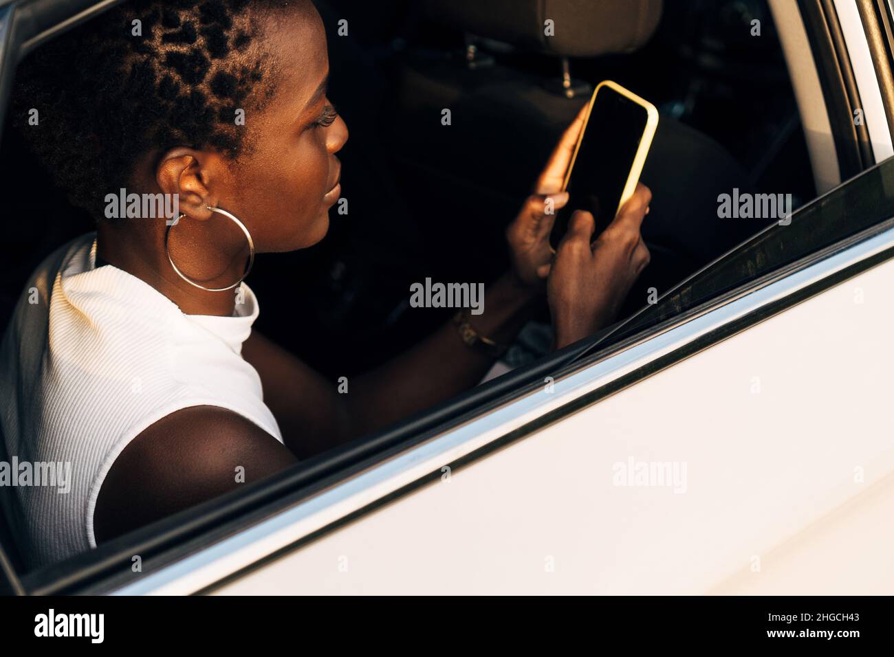 Woman using a mobile phone while traveling in the back seat of a car. Stock Photo