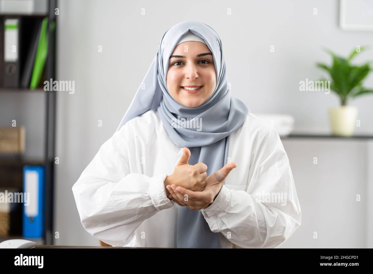 Happy Woman Wearing Hijab Learning Sign Language Stock Photo