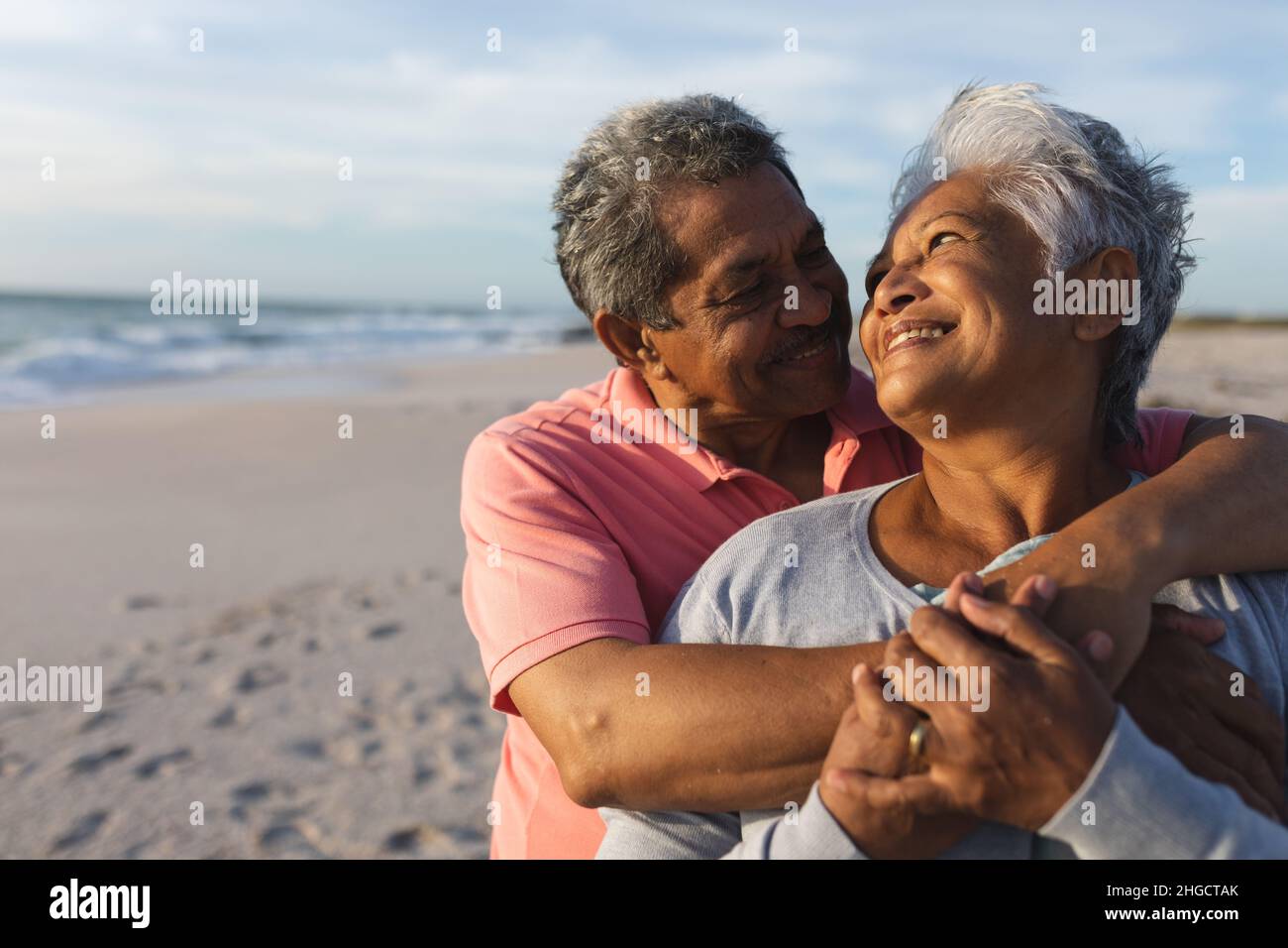 Happy senior biracial couple looking at each other while embracing during sunset Stock Photo