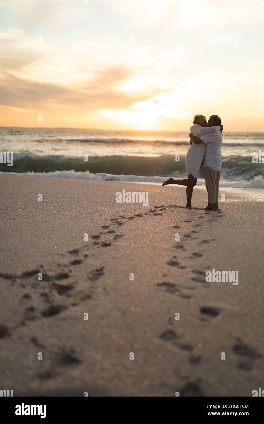 Full Length Of Affectionate Newlywed Biracial Couple Kissing While Standing At Beach During