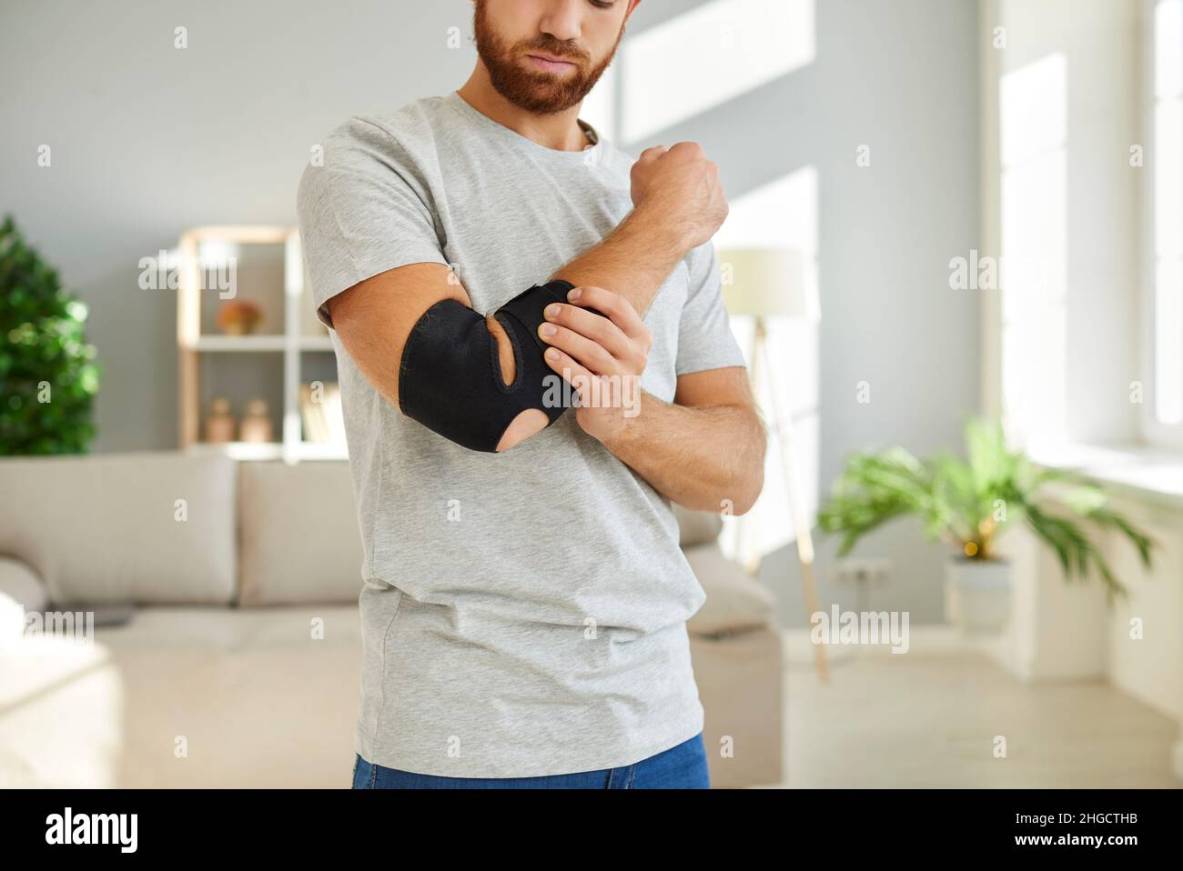 Man wears bandage on his elbow which serves as fixator to restore and relieve joint pain Stock