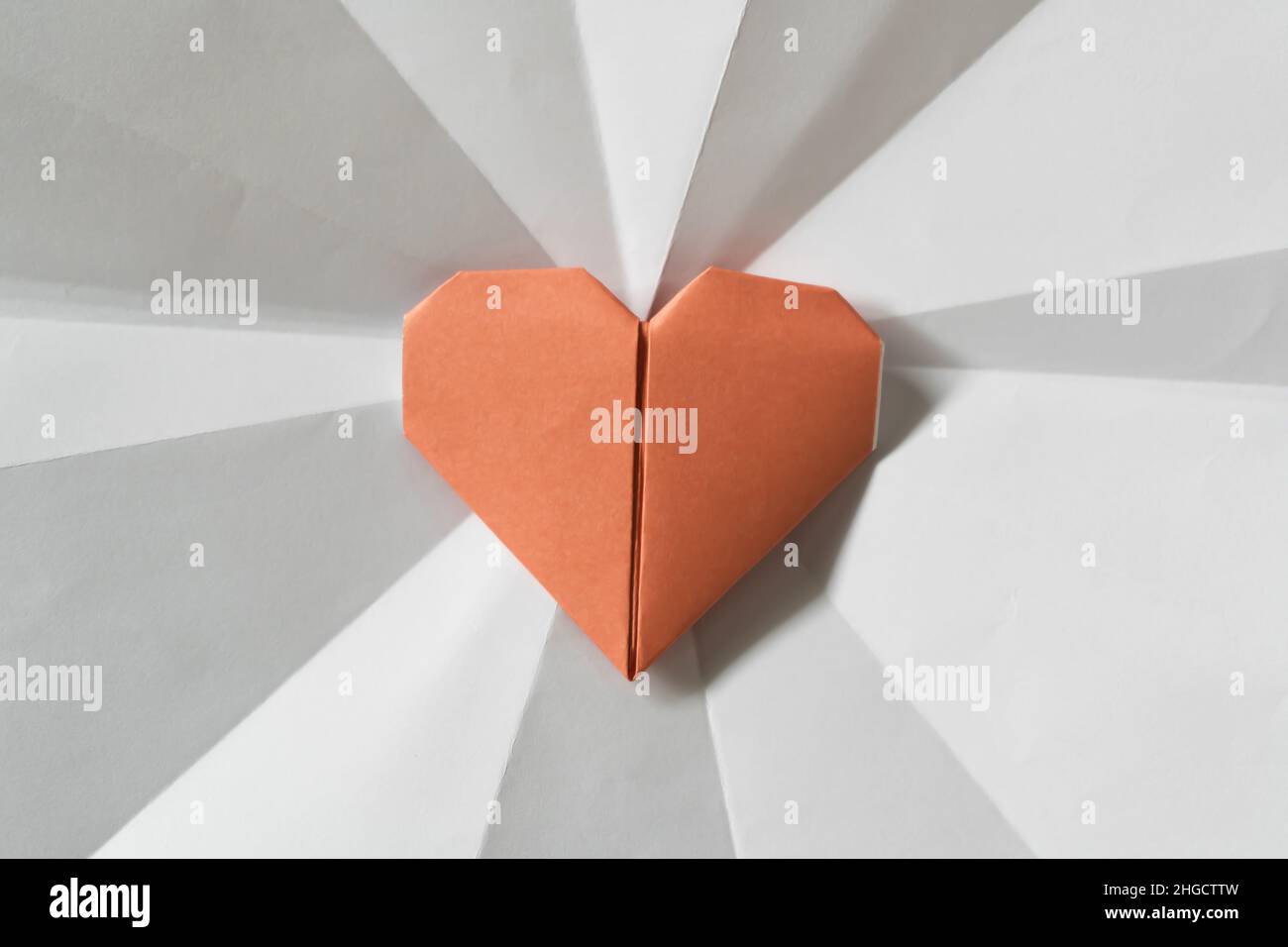 Origami heart on white paper with leading line Stock Photo