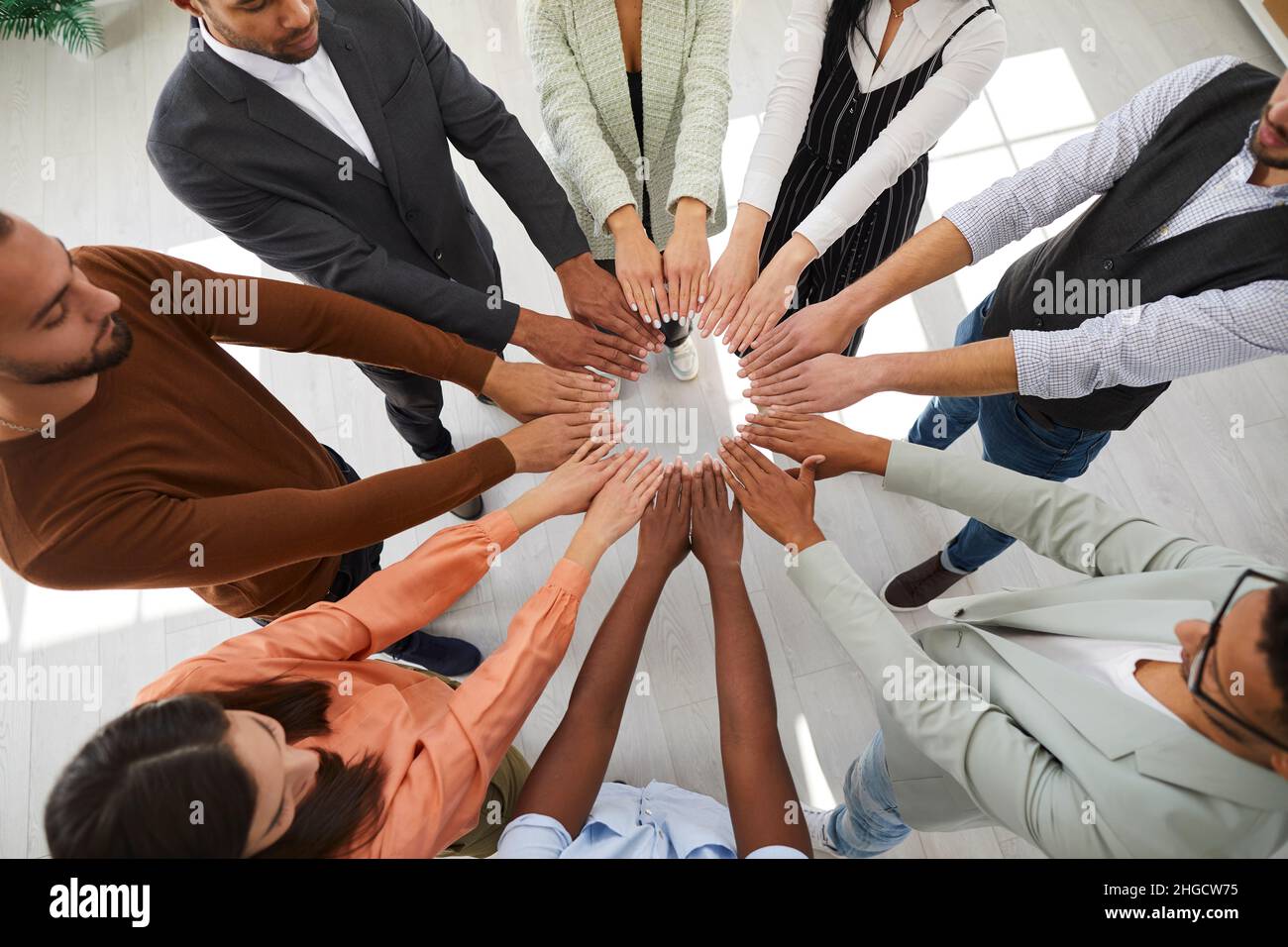 Diverse employees join hands engaged in teambuilding Stock Photo