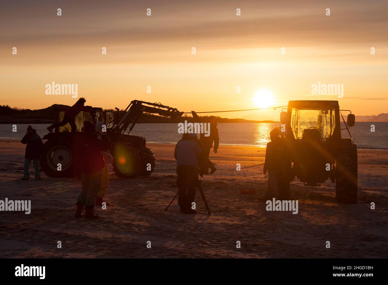 Playing with slack line between two tractors on the beach in Lofoten islands, northern Norway in the sunset Stock Photo
