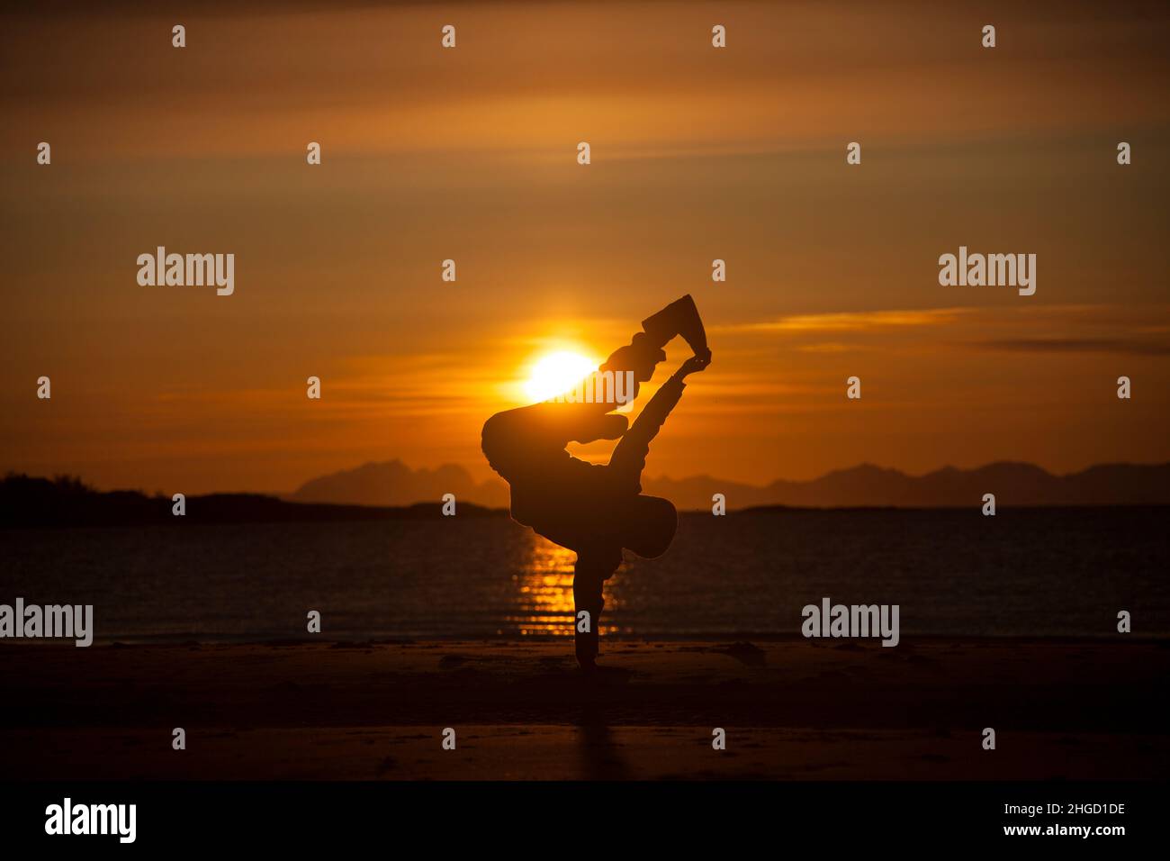 People having fun, and do acrobatics in the sunset on the beach in Lofoten islands, Norway Stock Photo