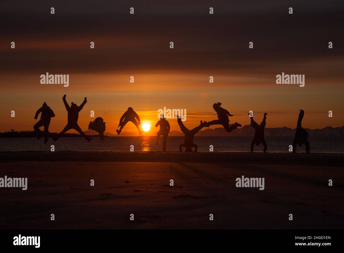 People having fun, and do acrobatics in the sunset on the beach in Lofoten islands, Norway Stock Photo