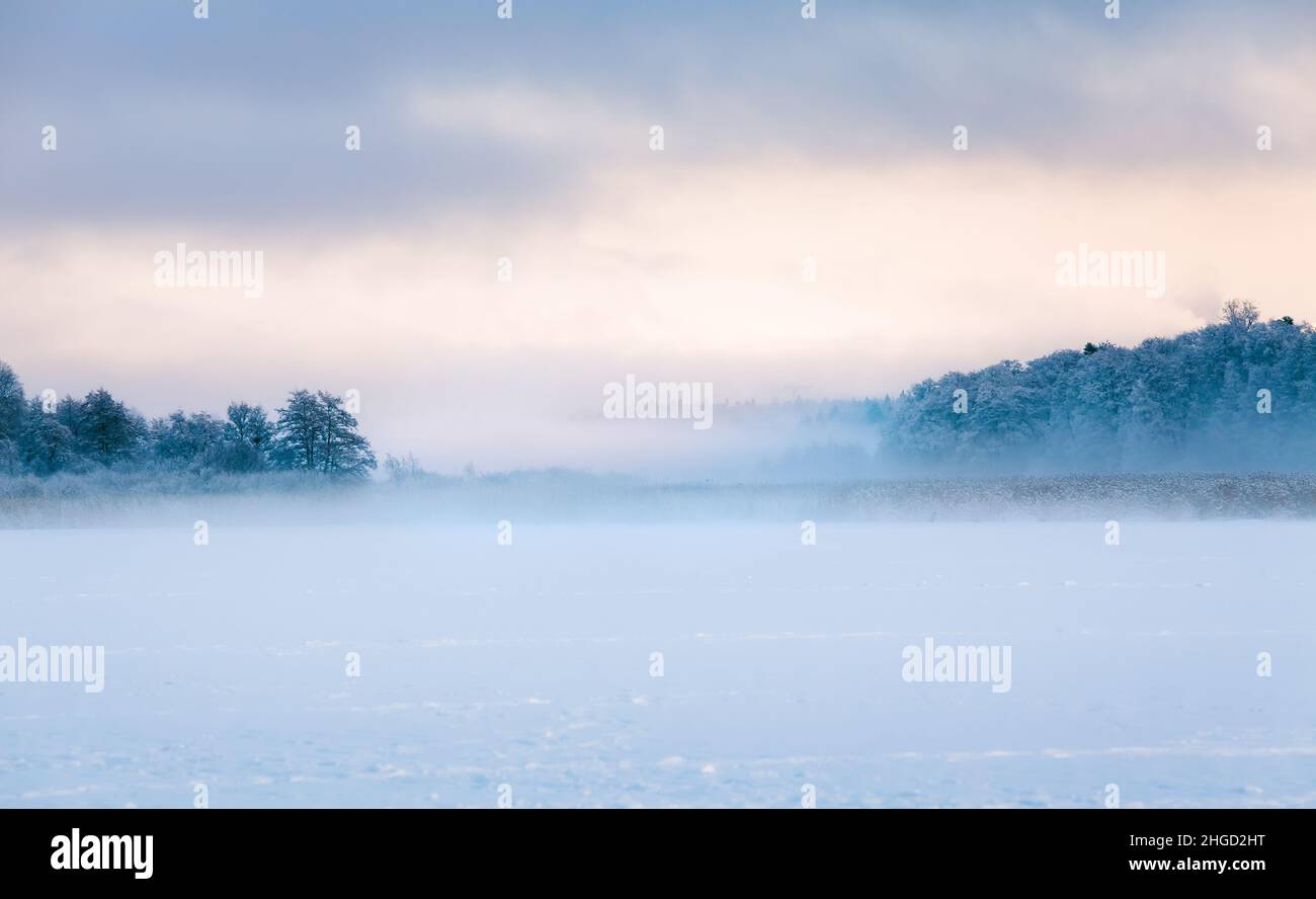 Foggy winter landscape during the sunset. Frozen sea. Stock Photo