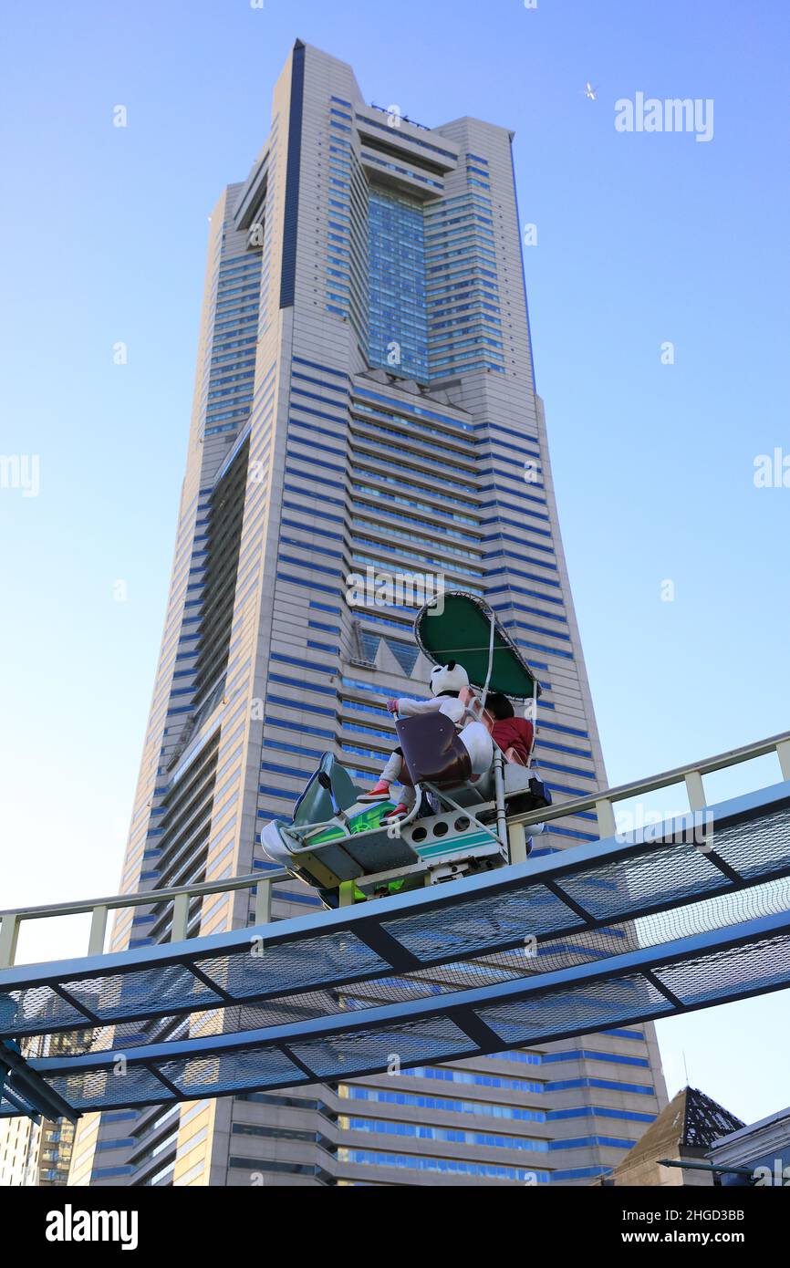 Mother and Child Having Fun at the Amusement Park Ride with Yokohama  Landmark Tower at the Background Stock Photo