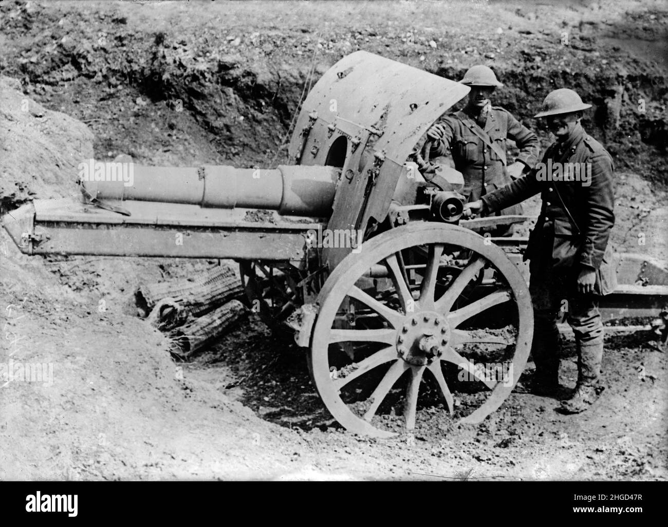A vintage photo of a captured German 15 cm schwere Feldhaubitze 13 (15 cm sFH 13) field howitzer during World War One with British soldiers posing next to it circa 1918. Stock Photo