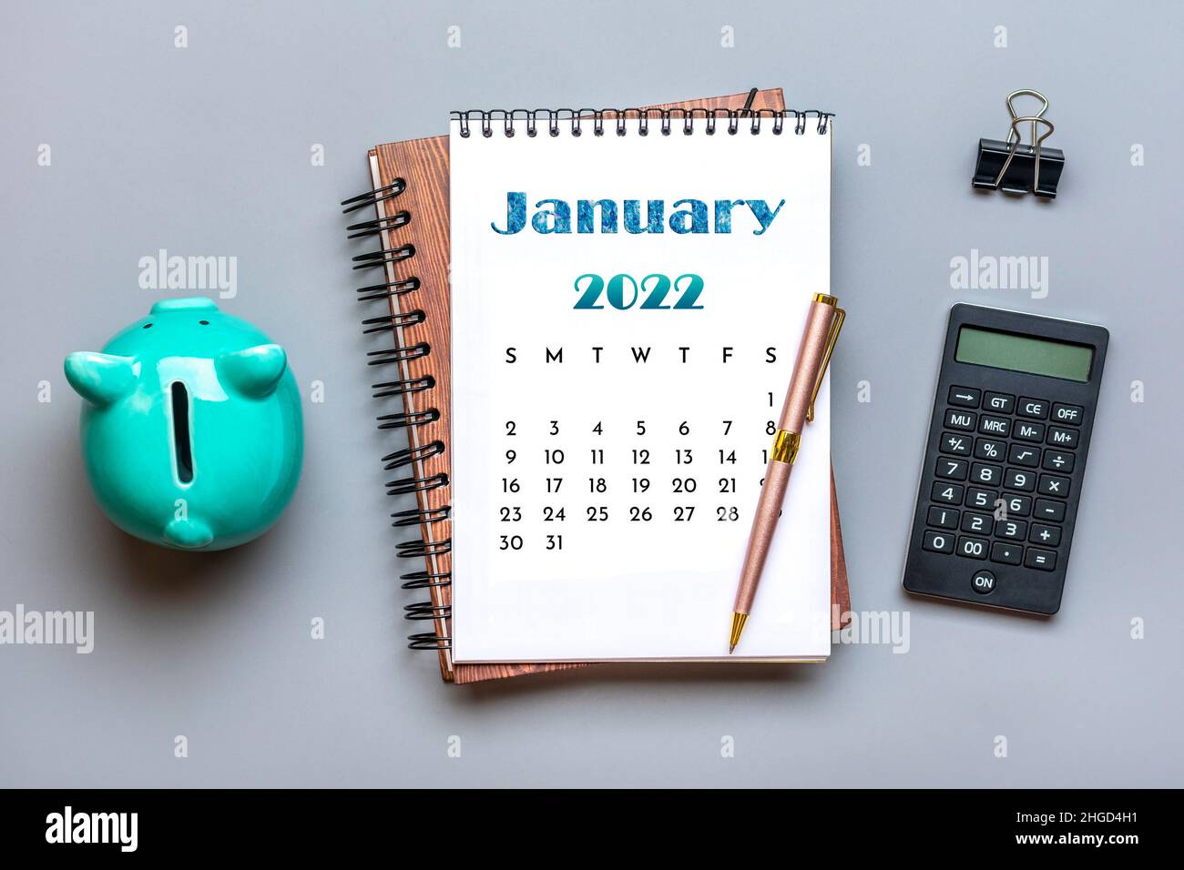 Open calendar January 2022, piggy bank, calculator, pen on gray