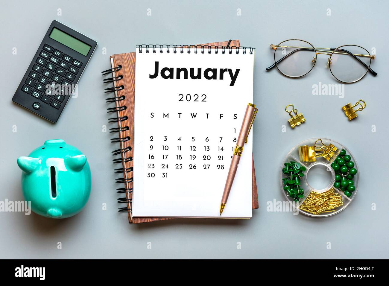 Open calendar January 2022, piggy bank, calculator, pen on gray