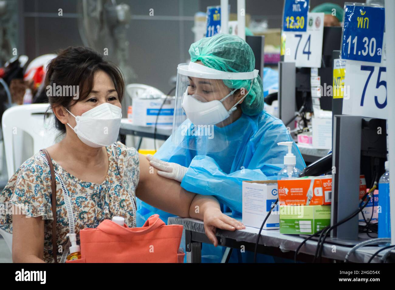 Bangkok, Thailand - Febuary 9, 2022 : asian doctor or nurse giving covid antivirus vaccine booster dose to senior woman patient wearing protective f Stock Photo