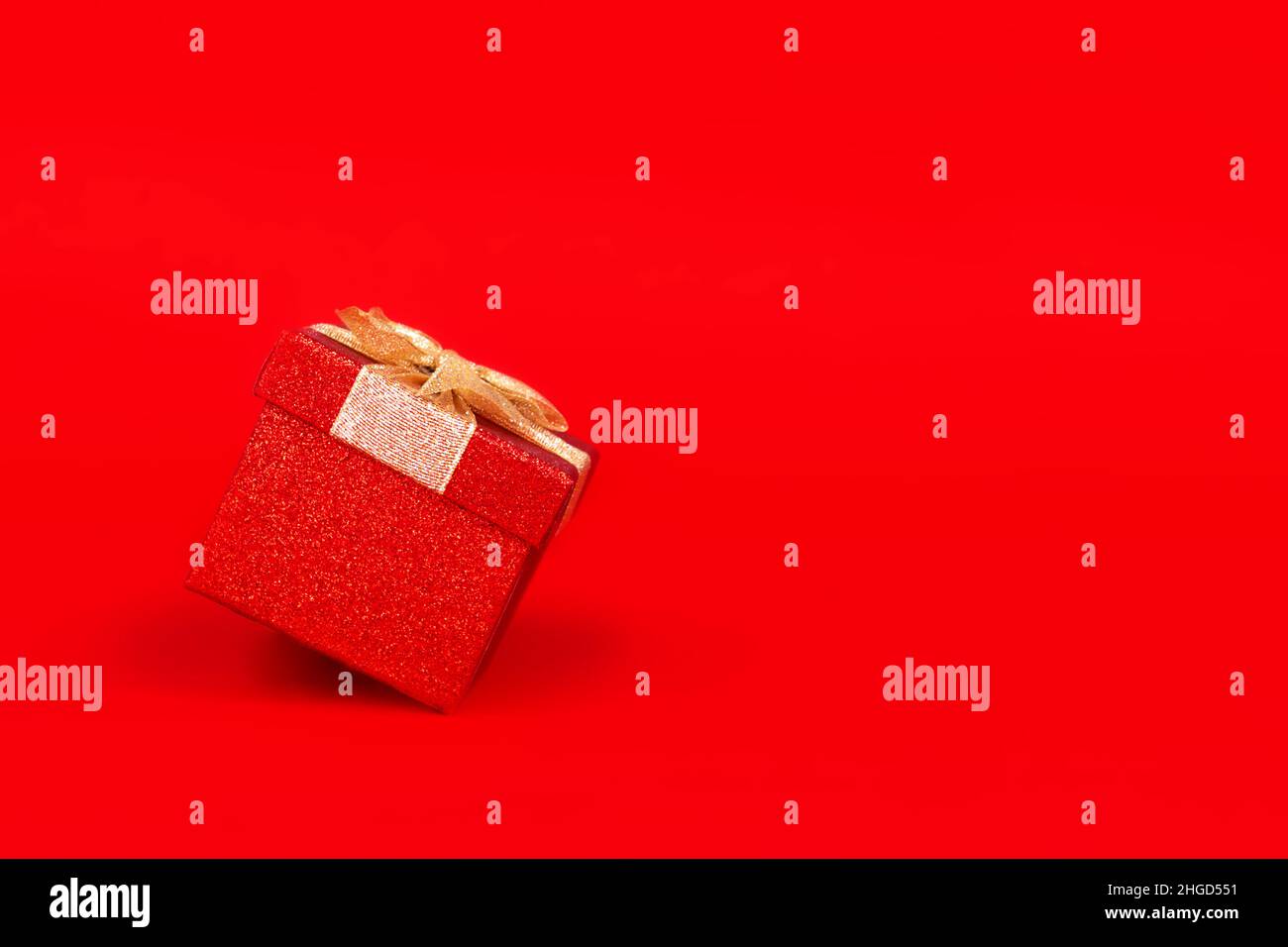 Gift box with golden bow. Red background. Stock Photo