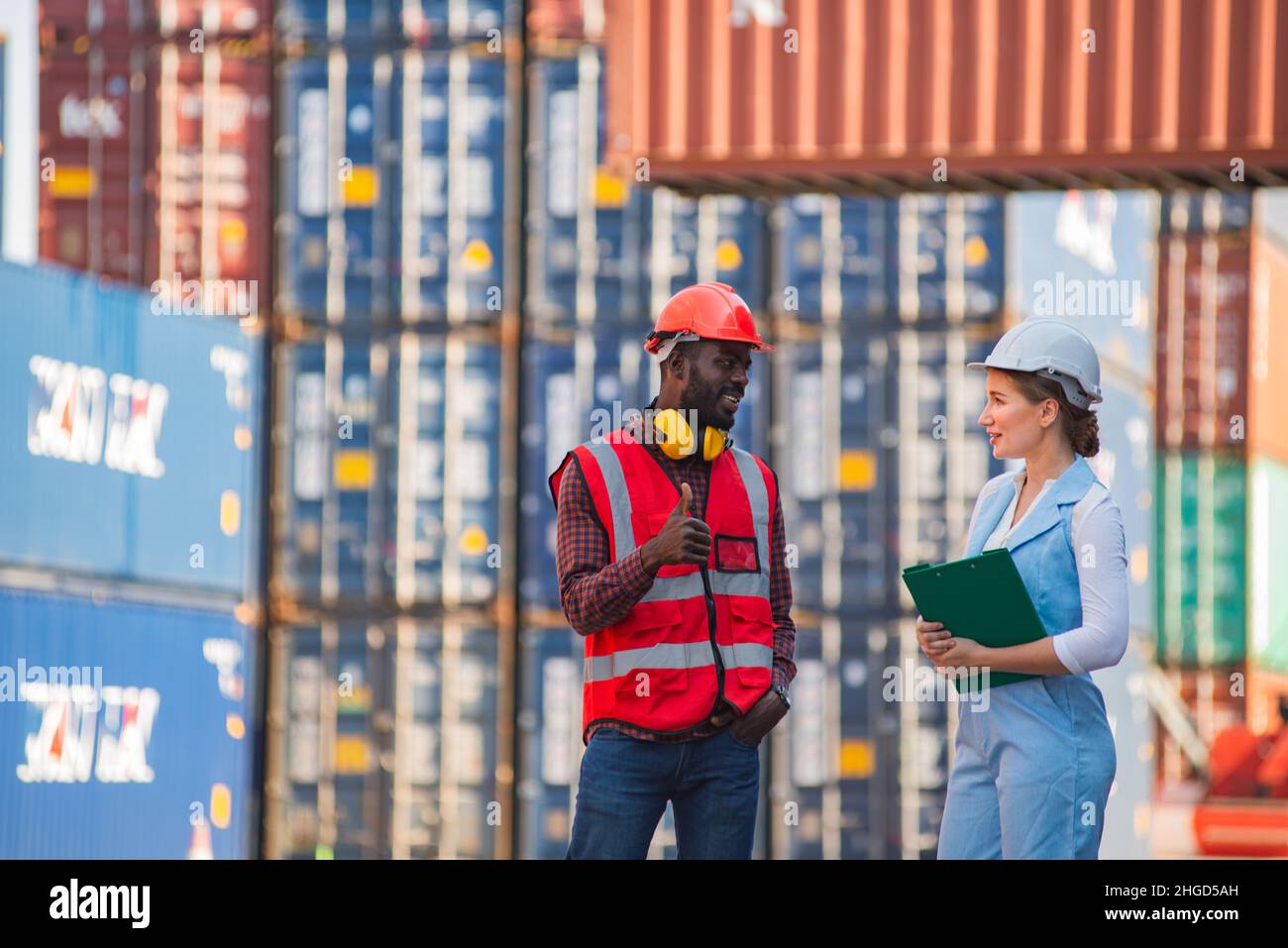 Businesswoman and engineer talking and checking loading Containers box from Cargo freight ship for import export. shipping in docks. Stock Photo
