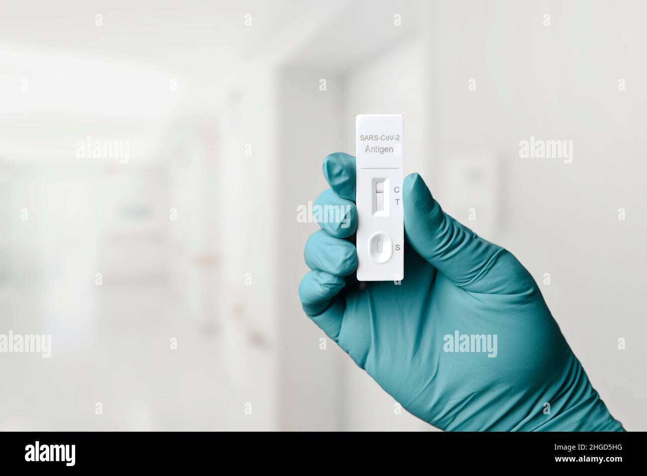 Gloved hand holding a rapid test device for COVID-19 with negative test result. Stock Photo