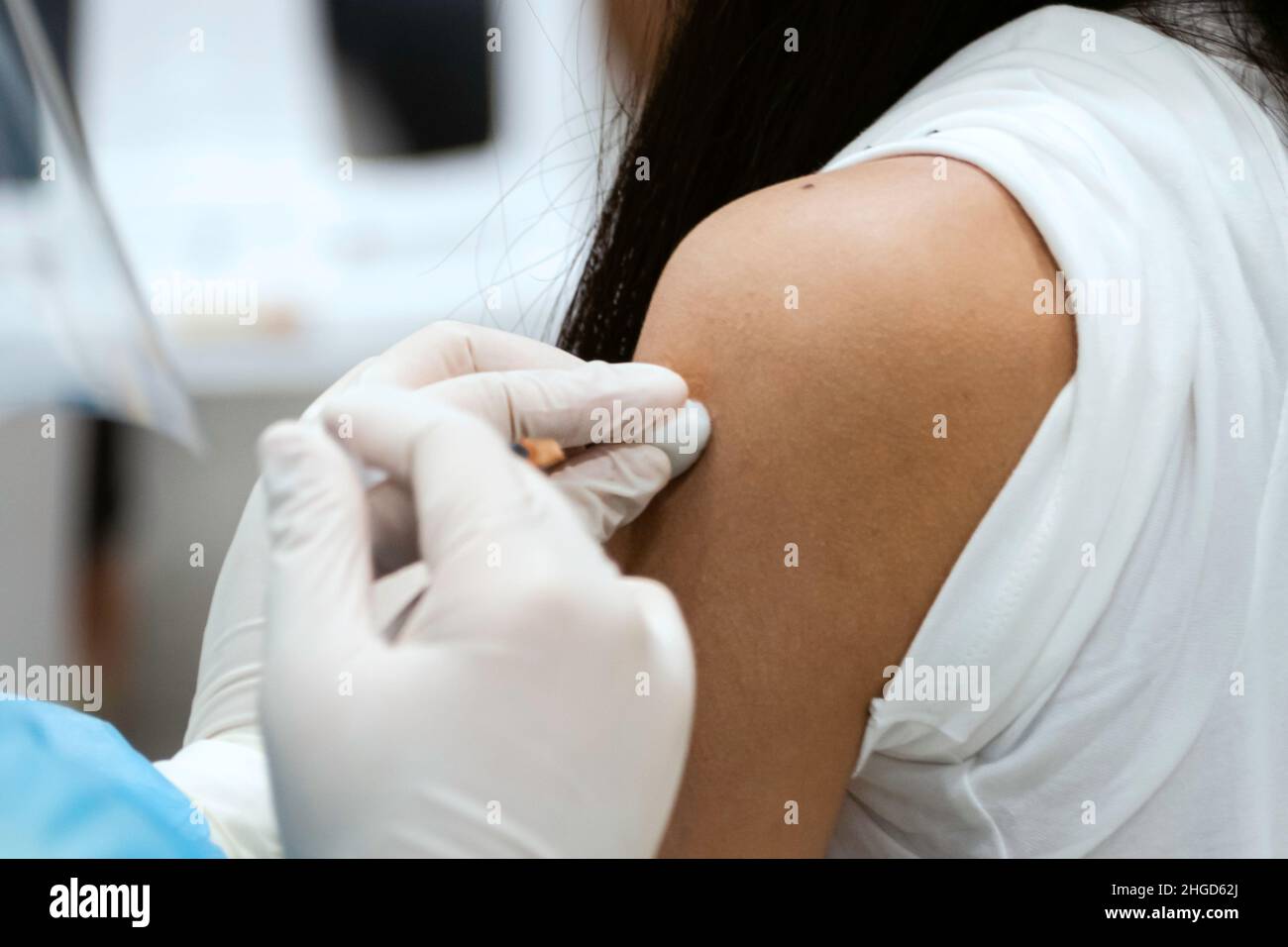 asian doctor giving omicron covid antivirus vaccine booster dose to woman. Stock Photo