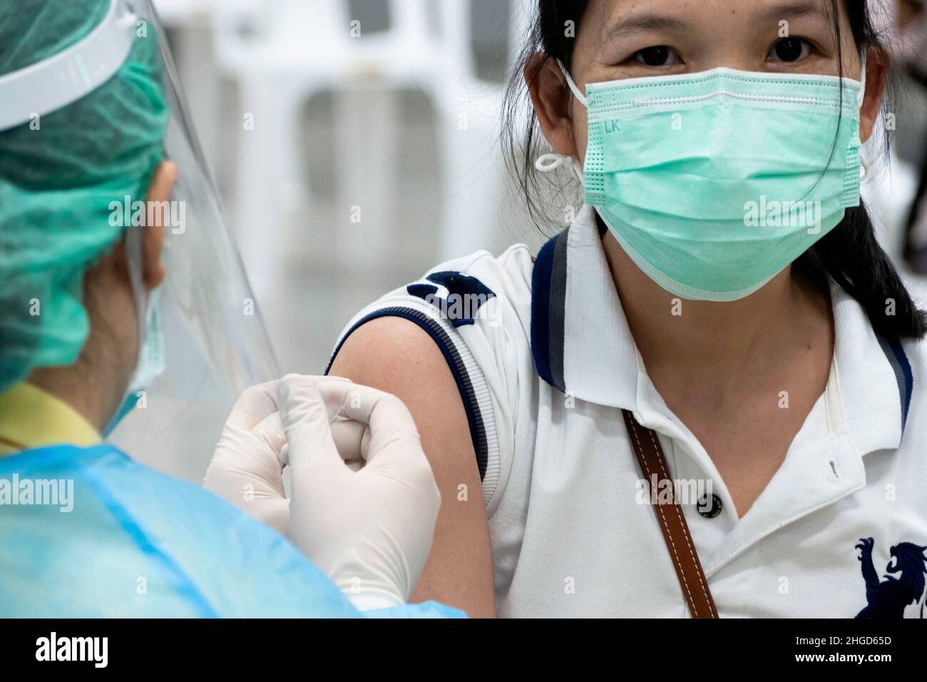 Bangkok, Thailand - January 25, 2022 : asian doctor giving omicron covid antiviral vaccine booster dose to woman patient. Stock Photo