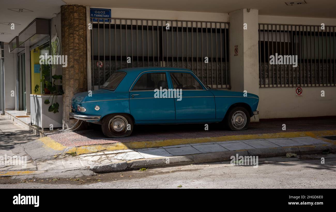 a damaged turquoise car staying under a house and waiting for reparation. Stock Photo