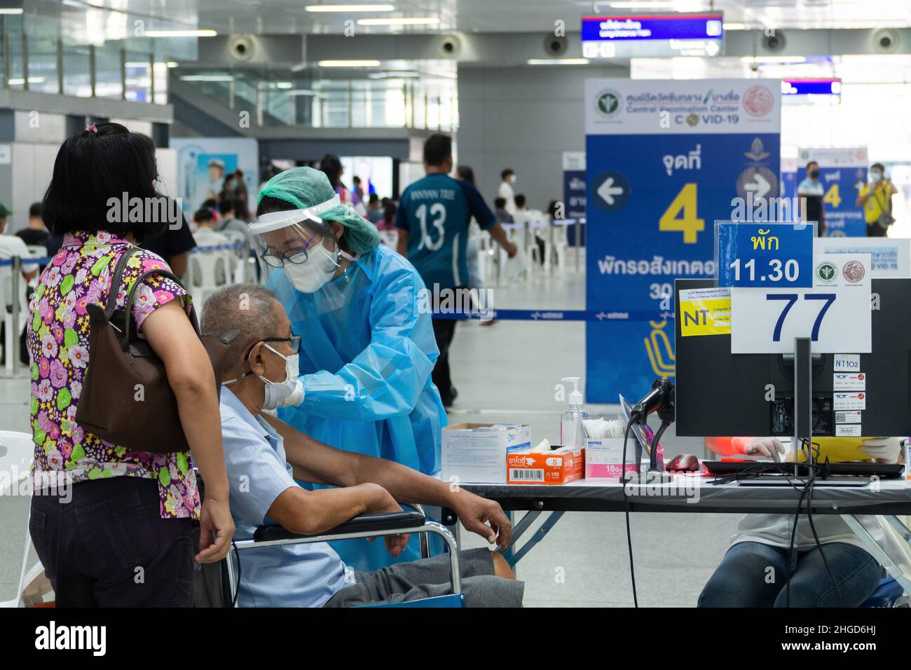 Bangkok, Thailand - January 25, 2022 : asian doctor giving covid antiviral vaccines shot booster to senior man patient wearing protective face mask. Stock Photo