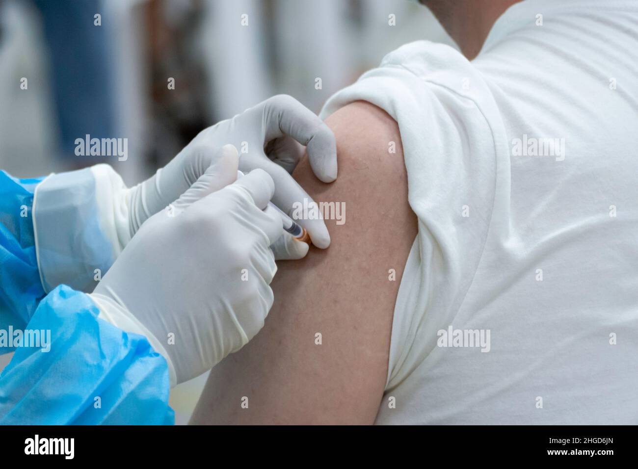 close up asian doctor giving omicron covid antivirus vaccine booster dose to woman patient wearing protective face mask from coronavirus. Stock Photo