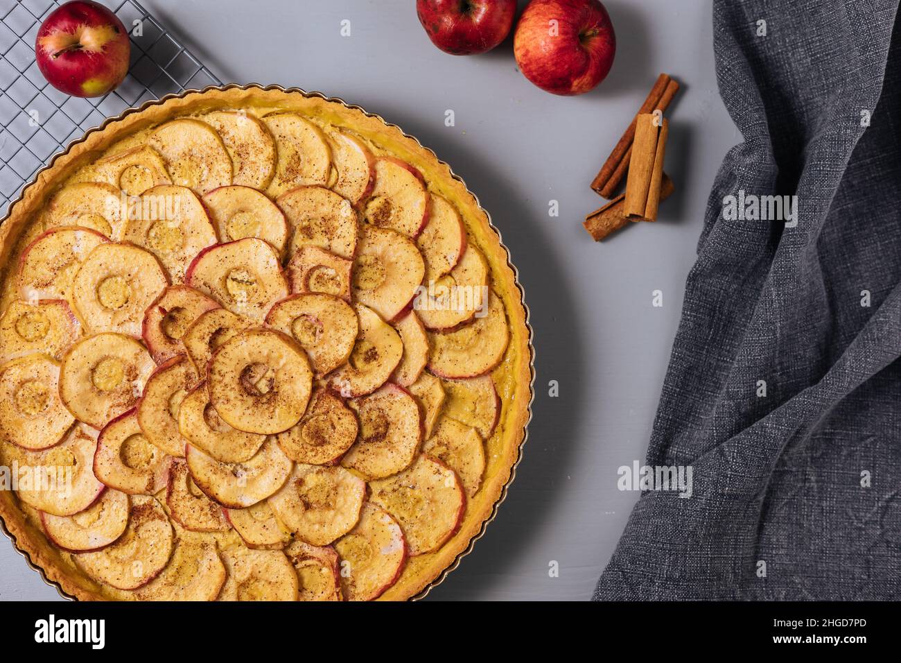 Top view of Classic french apple tart on a grey background with apples and cinnamon sticks Stock Photo